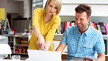 duas pessoas num escritório trabalhando no computador.