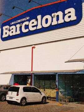 Galpão branco com placa azul no topo com o texto Lar & Construção Barcelona