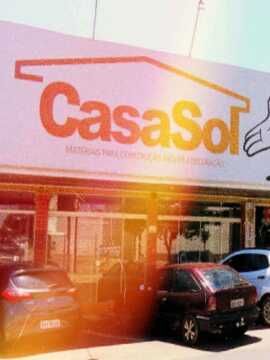 Loja CasaSol com placas na parte superior com a logo e um sol sorridente e veículos estacionados em frente e