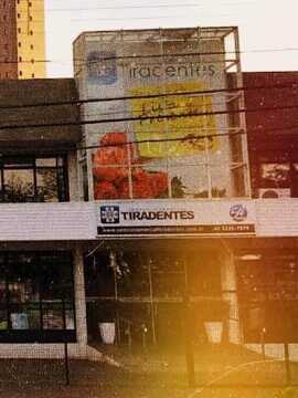 Foto da fachada do Centro Comercial Tiradentes com estacionamento em frente